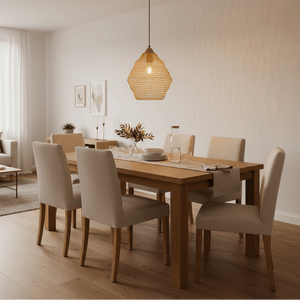 Gold wire-mesh pendant light hanging above a wooden dining table set with plates and glasses.