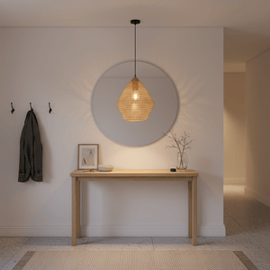 Gold mesh pendant light hanging above a wooden console table with decor items and a round mirror.