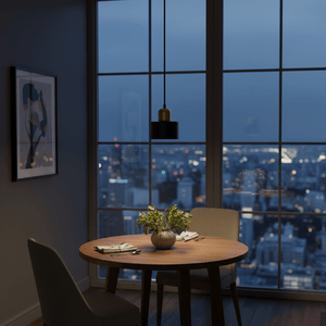 Cannon Black & Gold Marble Pendant Light hanging above a round wooden dining table with a city view at dusk.