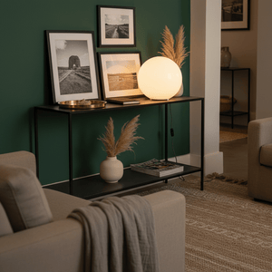 Global Table Lamp on a black console table with framed photos, a vase, and a cozy throw.
