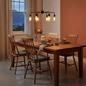 A dining table set with bowls and plates, illuminated by a stylish pendant light with amber bulbs.