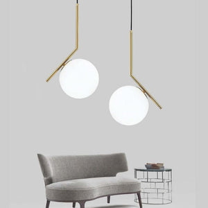 Two Humpty Large Pendant Lights with frosted glass shades hang above a modern gray sofa and glass side table.