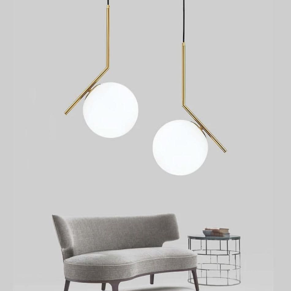 Two Humpty Large Pendant Lights with frosted glass shades hang above a modern gray sofa and glass side table.