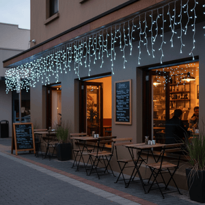 Cool white twinkling icicle lights hanging above a café entrance, enhancing outdoor ambiance.