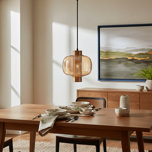 Gold glass pendant light hanging above a wooden dining table set with plates and cutlery.
