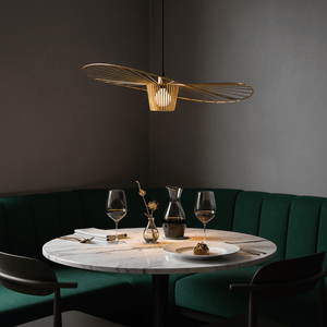 Stylish gold pendant light hanging over a marble dining table with green seating, creating an elegant ambiance.