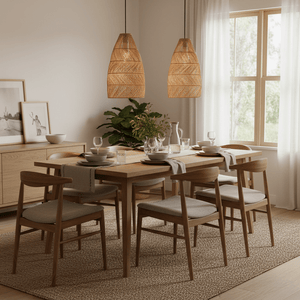 Rattan pendant lights hanging above a wooden dining table set with plates and glasses, surrounded by chairs.