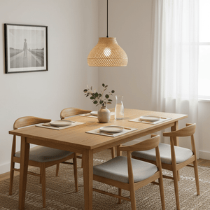 Hand-woven rattan and bamboo pendant light hanging above a wooden dining table set with plates and a vase.
