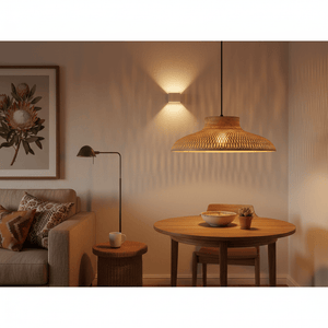 Woven bamboo rattan pendant light hanging above a wooden dining table with a bowl and plant.