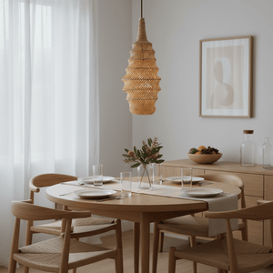 Woven rattan pendant light hanging above a round wooden dining table set for a meal.