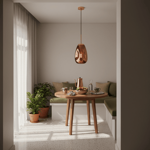 Copper teardrop pendant light hanging over a round wooden dining table in a modern nook
