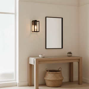 Bedford Outdoor Wall Light mounted beside a mirror on a light wall, illuminating a wooden table with decor.