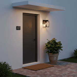 Outdoor wall light illuminating a front door area with a potted plant and welcome mat.