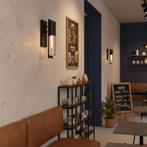 Industrial iron and clear glass wall light illuminating a cozy café interior with seating and decor.