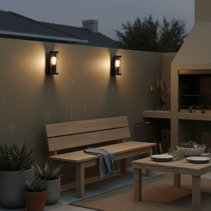 Outdoor scene featuring two aluminium wall lights illuminating a wooden bench and dining table on a patio.