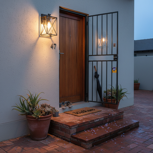Black metal lantern with textured glass glowing beside a wooden front door, brick steps and potted succulents
