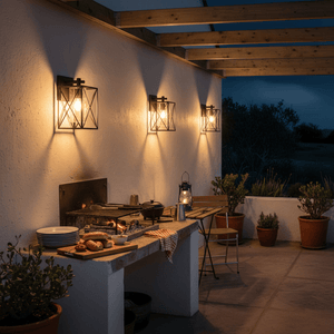 Three black metal lantern wall lights cast warm downward light over a patio braai area.