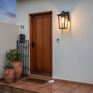 Contemporary outdoor wall light mounted beside a wooden door, illuminating the entrance with a warm glow.