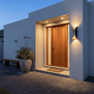 Titania Outdoor LED Wall Light illuminating a modern entrance with a wooden door and potted plants.