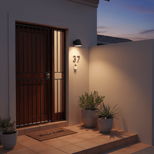 Outdoor wall light illuminating a home's entrance with potted plants and a welcome mat.