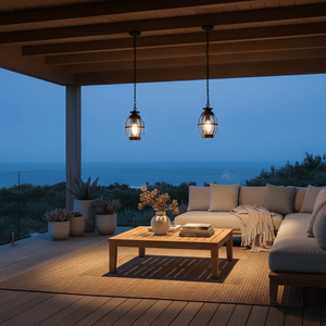 Two Sey Outdoor Pendant Lights hang above a wooden table on a patio, illuminating a cozy seating area with ocean views.