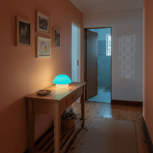 Mushroom cap night light glowing softly on a wooden console table in a cozy hallway.