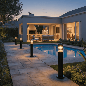 Montague 600 Bollard Light illuminating a pathway beside a pool, enhancing outdoor ambiance at dusk.