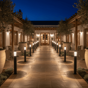 A pathway lined with Montague 1100 bollard lights, illuminating a modern outdoor space at night.