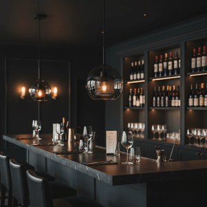 Smoke glass and black mesh 25 cm ball pendant hanging above a dark bar counter in a modern dining setting