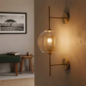 Gold New York Ball Wall Light mounted on a textured wall, illuminating a cozy living space with a green bench and wooden