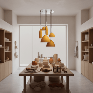 Orange cluster pendant with six hanging glass shades over a wooden dining table displaying pottery and textiles.