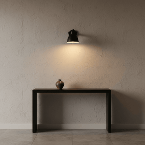 Adjustable black wall lamp illuminating a console table with a decorative vase.