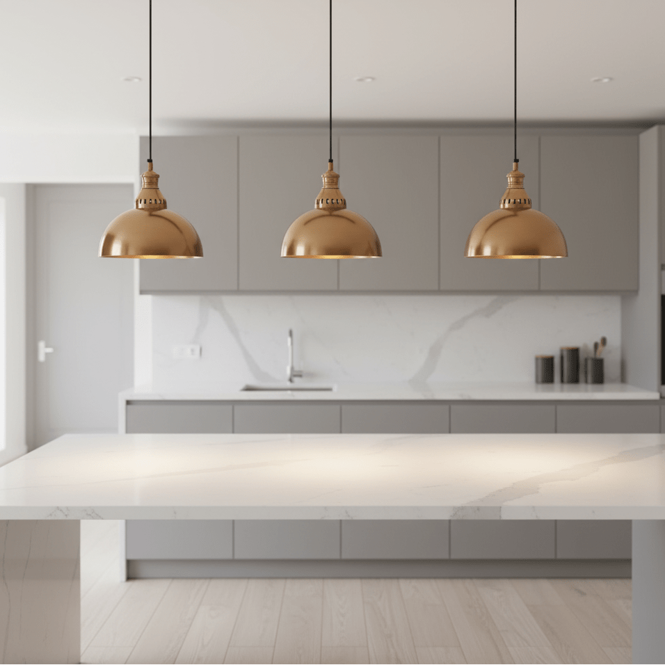 Three antique brass dome-shaped pendant lights hanging above a modern kitchen island with a marble countertop.