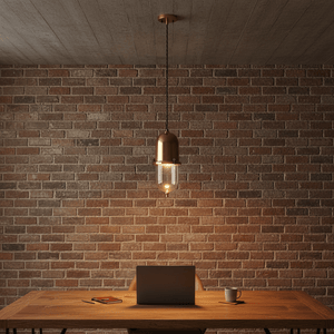 Skylar Hanging Lamp in antique brass above a wooden table, featuring a clear glass enclosure and domed cap.
