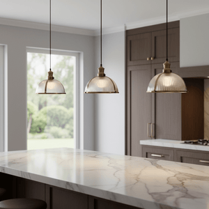 Three Salina Hanging Lamps in antique brass above a kitchen island, showcasing ribbed glass shades.