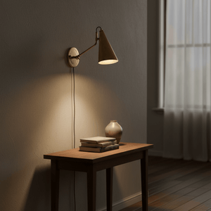 Antique brass wall lamp illuminating a wooden table with books and a vase.