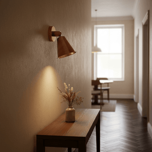 Antique brass wall lamp illuminating a hallway with a wooden table and vase of dried flowers.