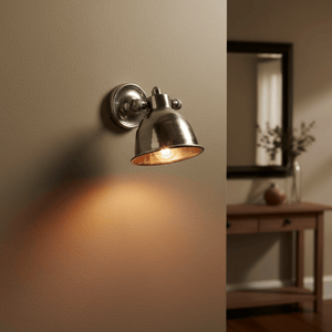 Antique silver wall lamp mounted on a beige wall, casting warm light with a stylish design.