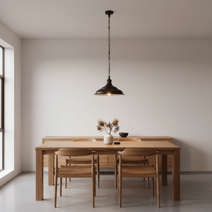 Medium matt black pendant lamp hanging above a wooden dining table with chairs and decor.