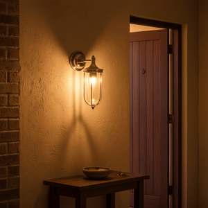 Antique silver wall lamp with clear glass diffuser illuminating a textured wall and wooden table.