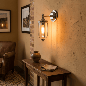 Antique silver wall lamp with clear glass shade illuminating a rustic interior with a wooden table and pottery.