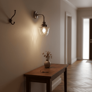 Antique silver wall lamp with cut glass design illuminating a hallway, beside a wooden table with a vase.