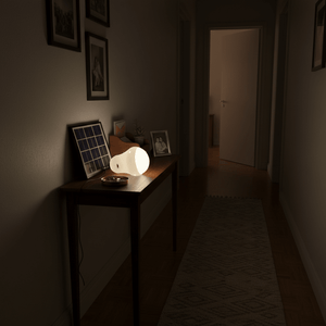 Portable solar light kit on a table in a dimly lit hallway, with a solar panel and framed photos.