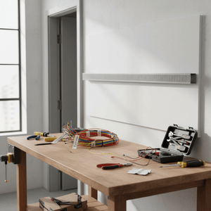 Grey slotted trunking mounted on a wall above a wooden workbench with tools and organized wires.