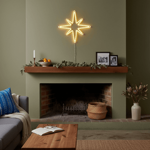 LED shining star motif above a fireplace, creating a warm festive atmosphere with decorative elements.