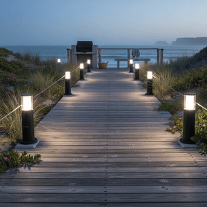 Wooden pathway leading to a beach with illuminated bolard lamps on either side.