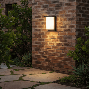 Lone Outdoor Wall Light mounted on a brick wall, illuminating a stone pathway surrounded by greenery.