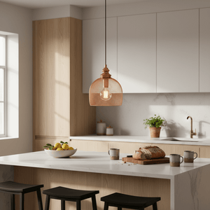 Copper mesh pendant light hanging above a kitchen island with fruit bowl and bread on a wooden board.
