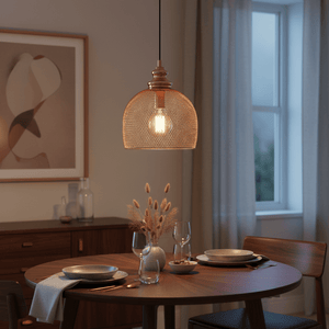 Copper mesh pendant light hanging above a wooden dining table set with plates and glasses, creating a warm ambiance.