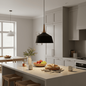 Black pendant light with wooden top hanging over a countertop with bread, fruit bowl, and mugs.